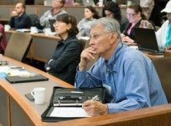 Audience paying attention to a lecture with older white male in foreground