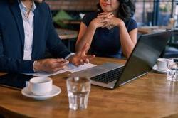 A man and a woman sit in a cafe, discussing among themselves.