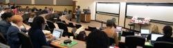 Wide photograph encompassing a large faculty audience seated in a lecture hall.